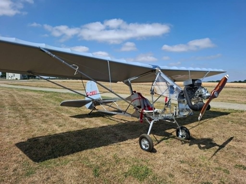 Completed Affordaplane parked on grass with a pilot standing nearby
